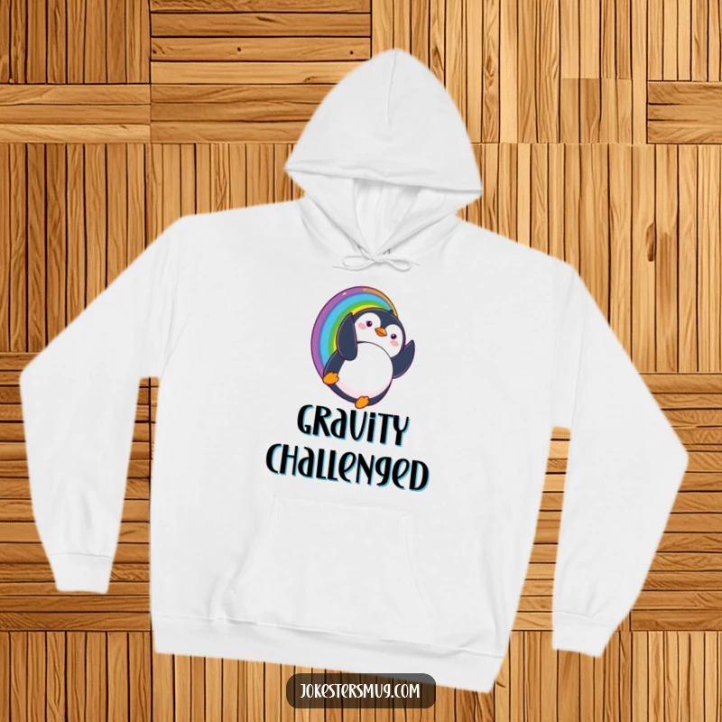 Funny hoodie featuring a penguin sliding down a rainbow and landing upside down with a surprised expression, perfect for cozy and whimsical humor.