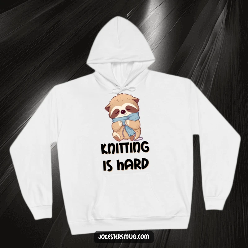 Funny hoodie featuring a sleepy sloth getting comically tangled in yarn while attempting to knit a scarf, radiating ultimate coziness.
